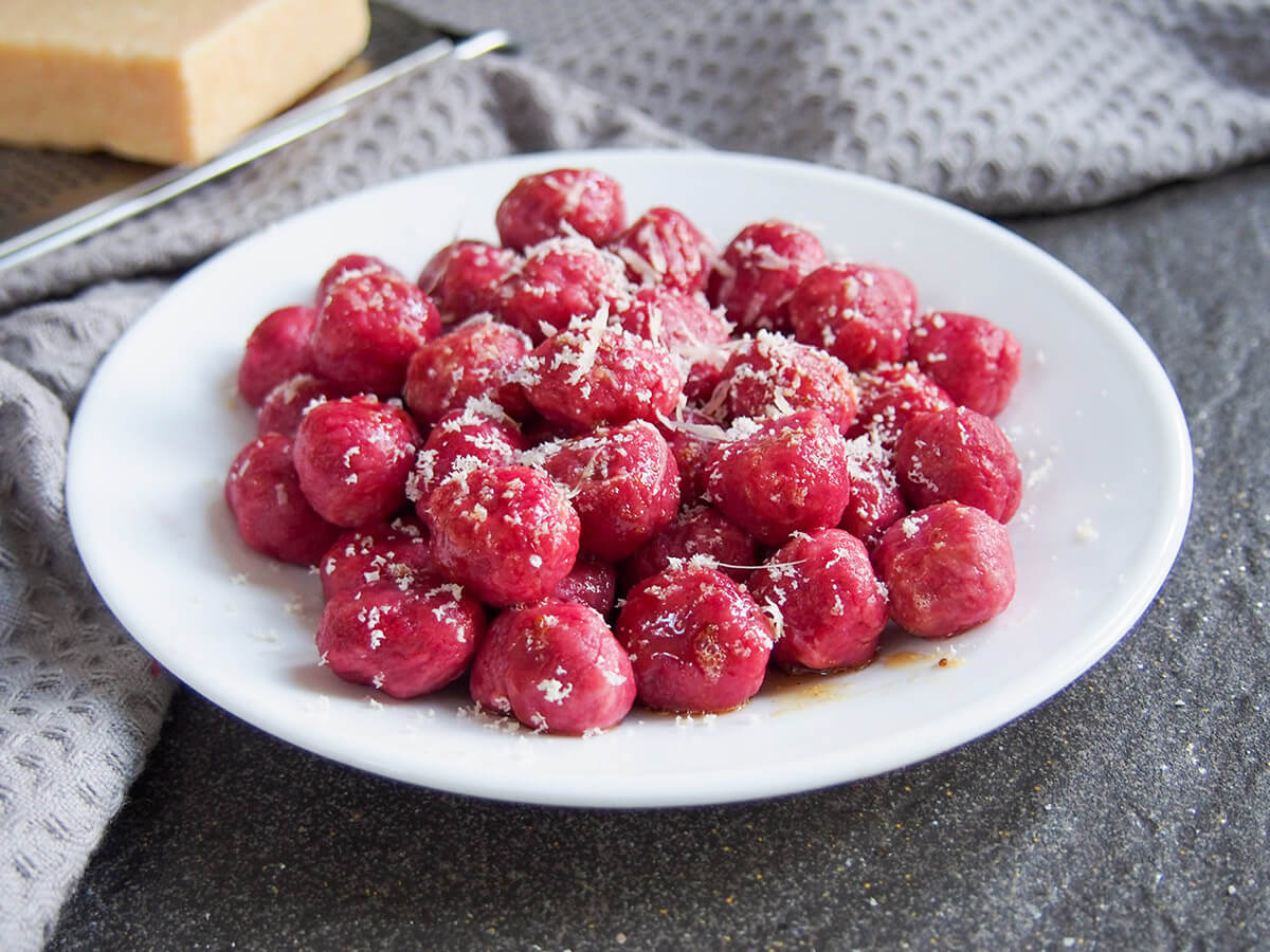 plate of beet gnocchi with cheese to side