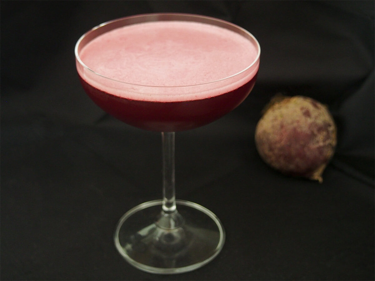 glass of beet negroni sour Halloween cocktail with beet in background