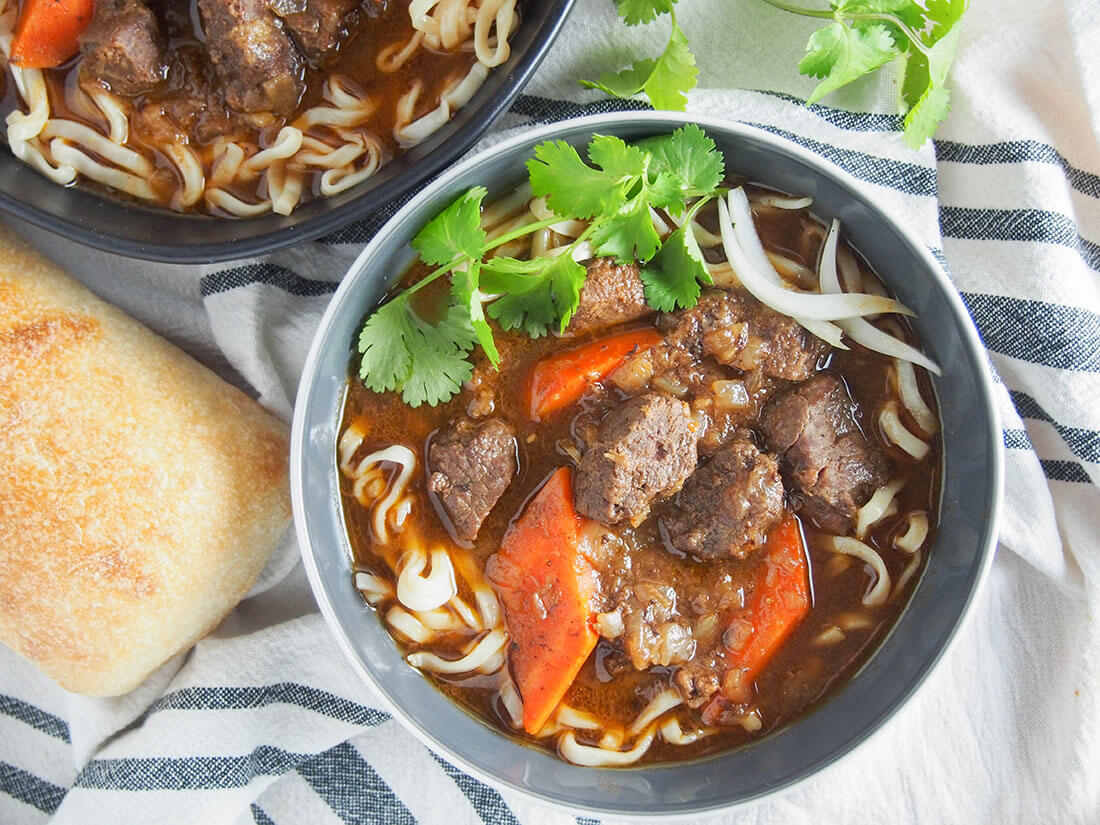 bowl of bo kho Vietnamese beef stew with bread to side