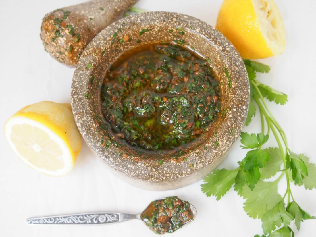 chermoula sauce in mortar from overhead with lemon and cilantro to side