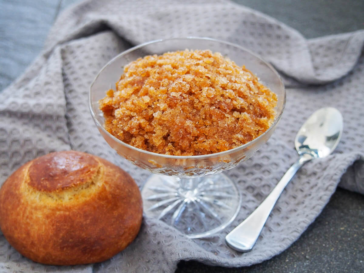 glass of coffee granita with brioche to one side and spoon to other