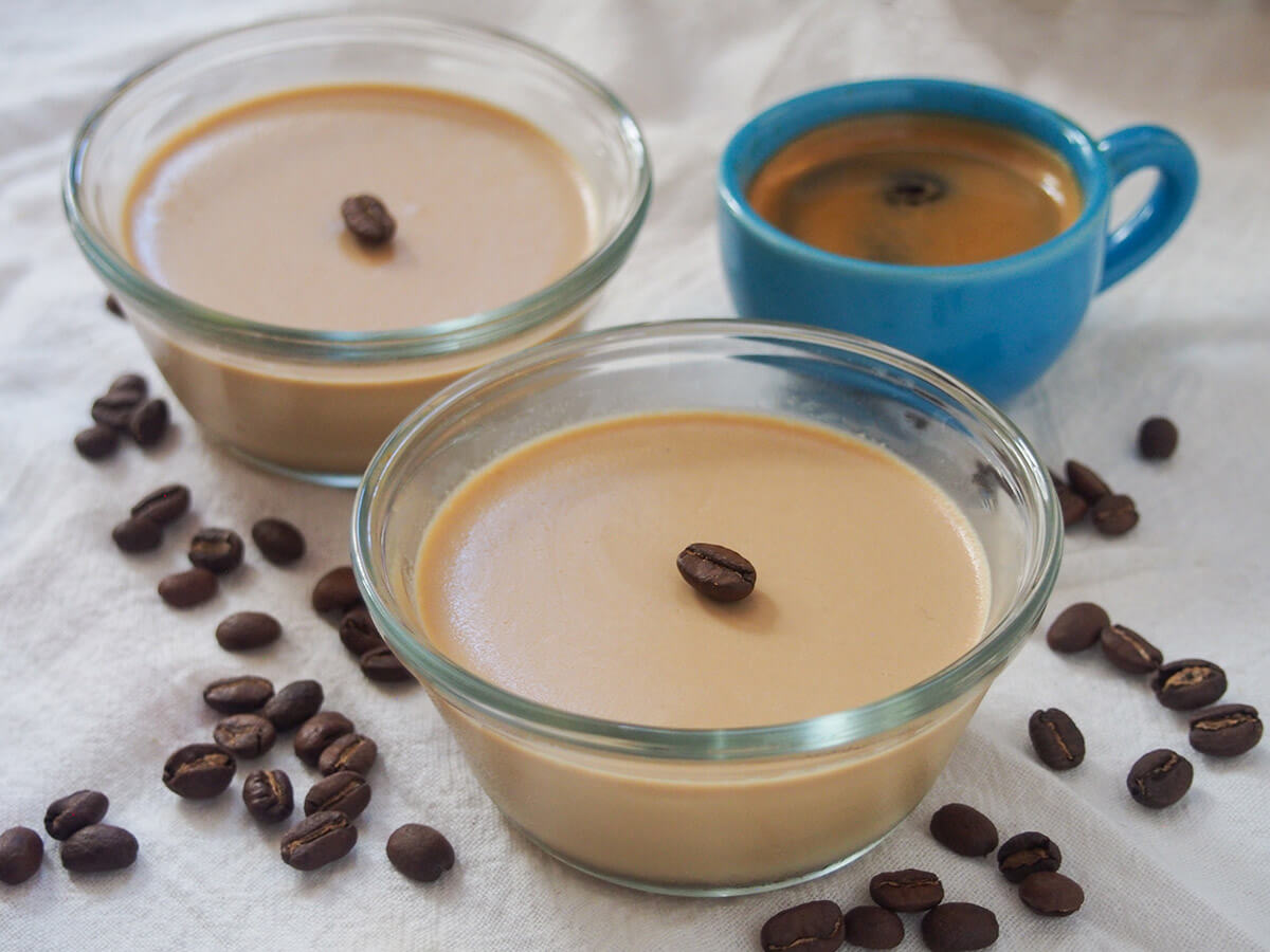 two dishes of coffee panna cotta with coffee beans around them