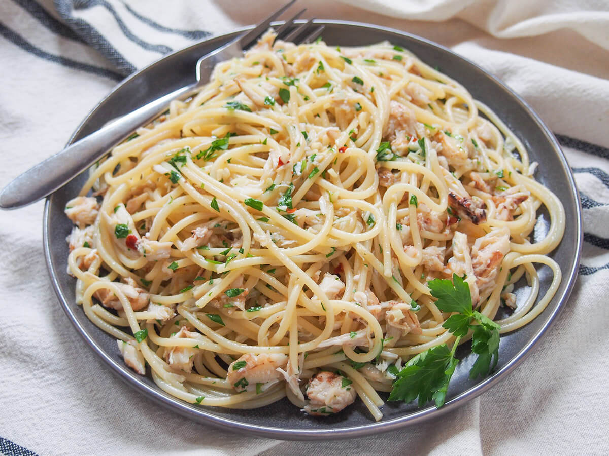 plate of crab pasta from side with fork at back of plate