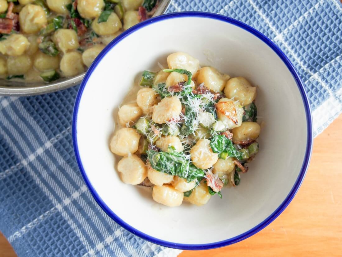 grocchi with creamy bacon sauce with spinach in bowl from overhead