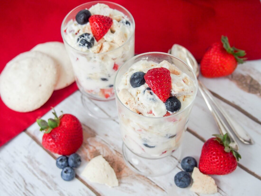 two glasses of Eton mess with fruit and meringue to side