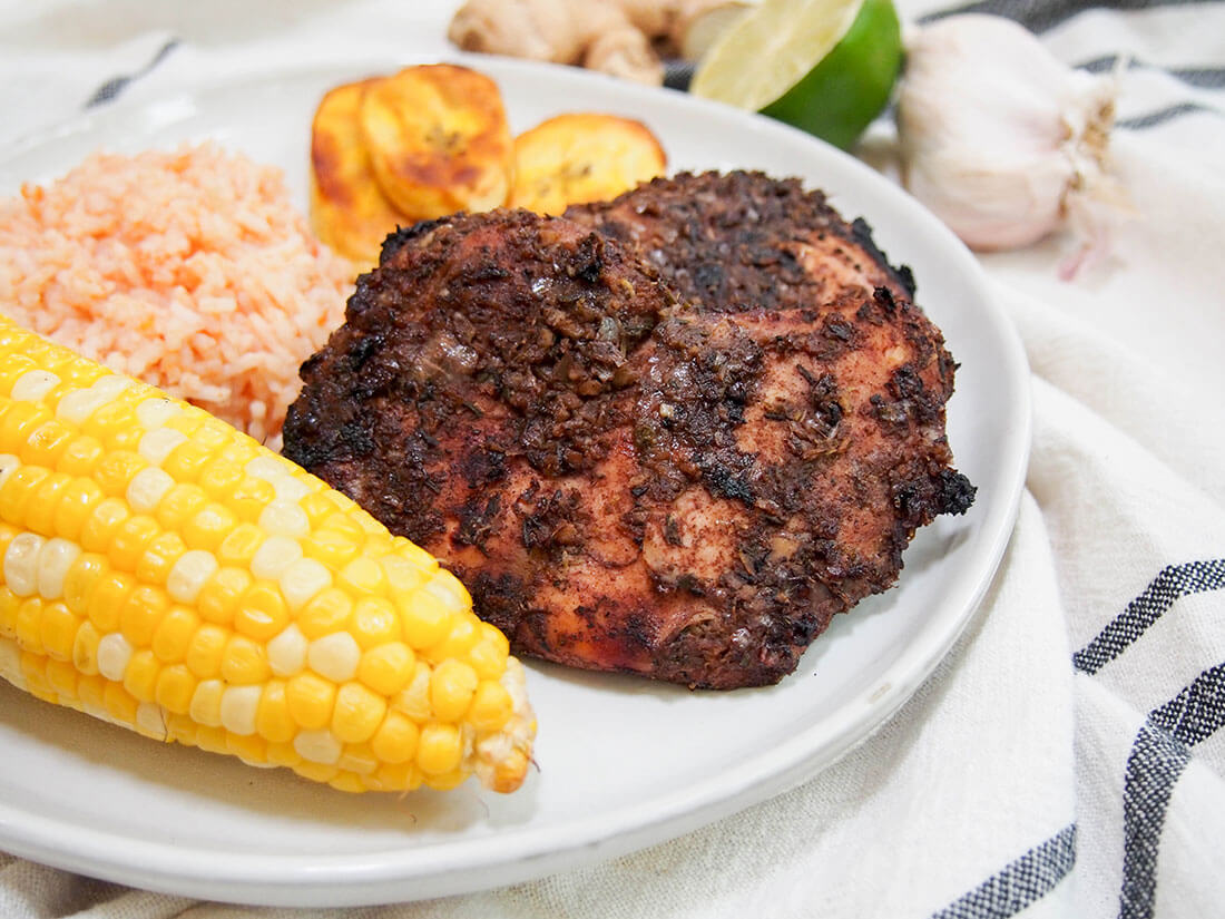 Jamaican jerk chicken with sides of corn, rice and plantain