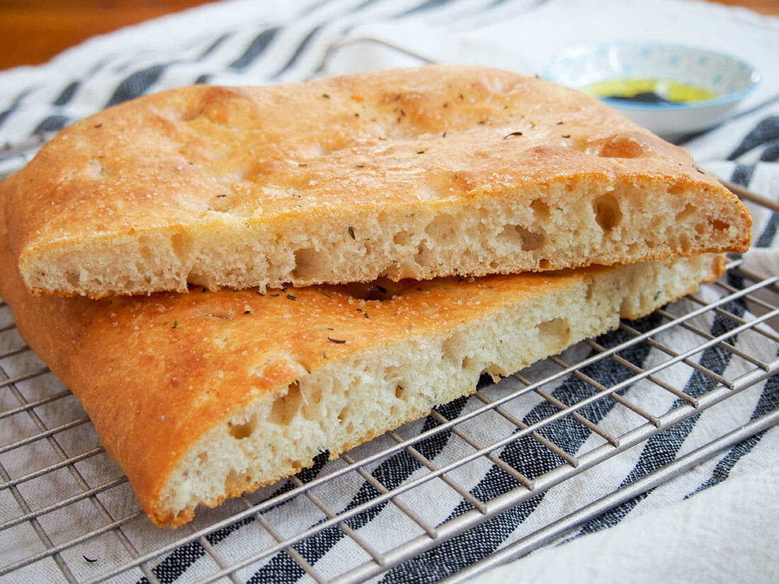 lemon thyme focaccia wish one part resting on top of other showing sliced edges