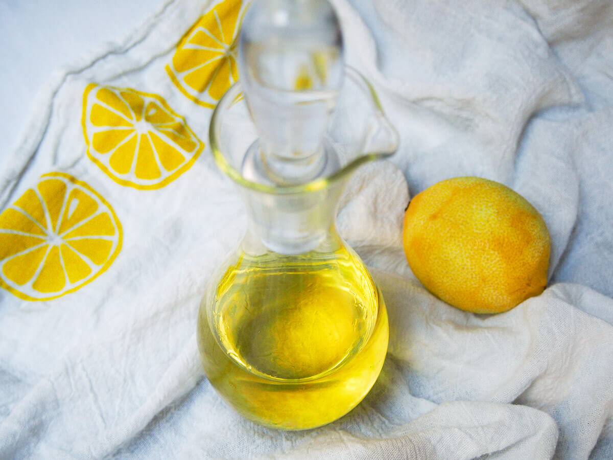 bottle of homemade limoncello with lemon to side