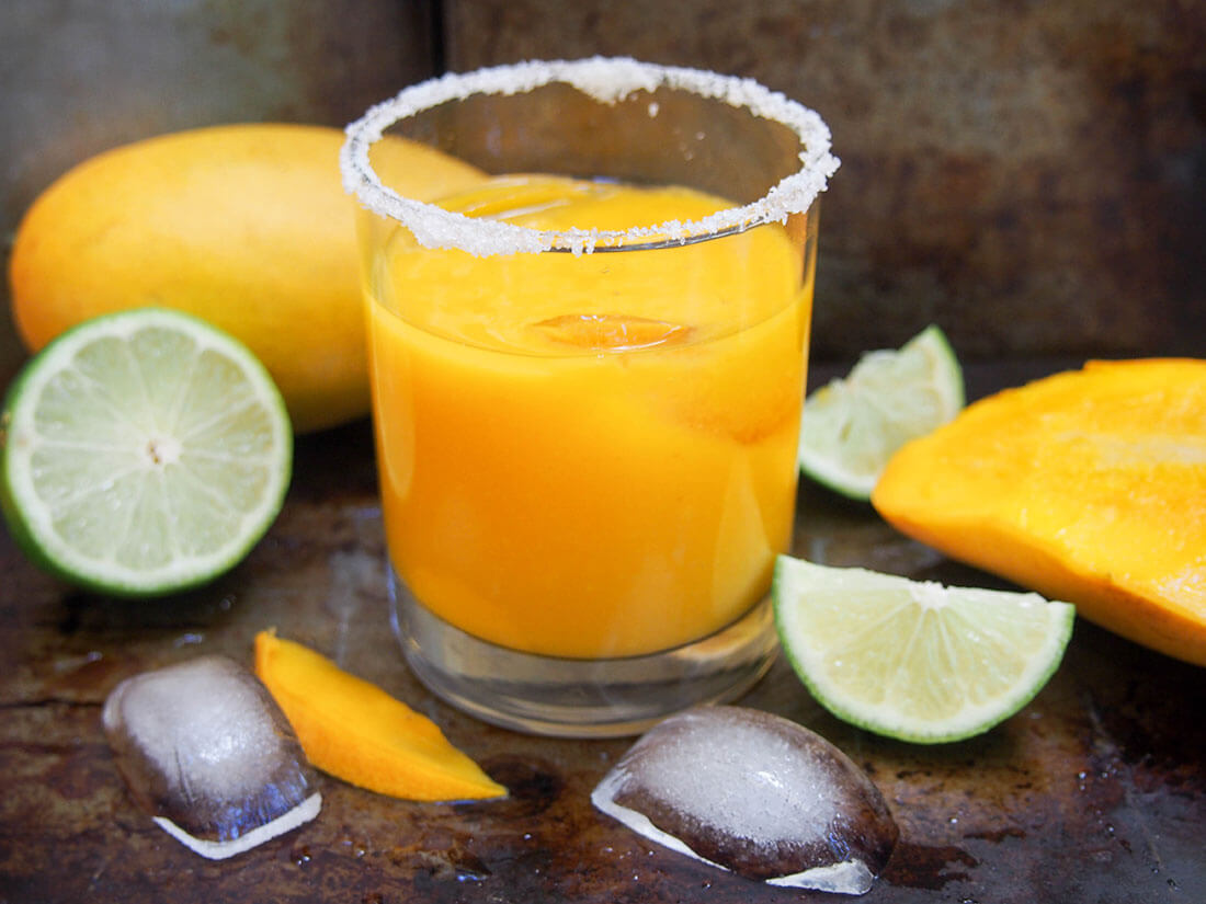 mango margarita with mango and lime to side