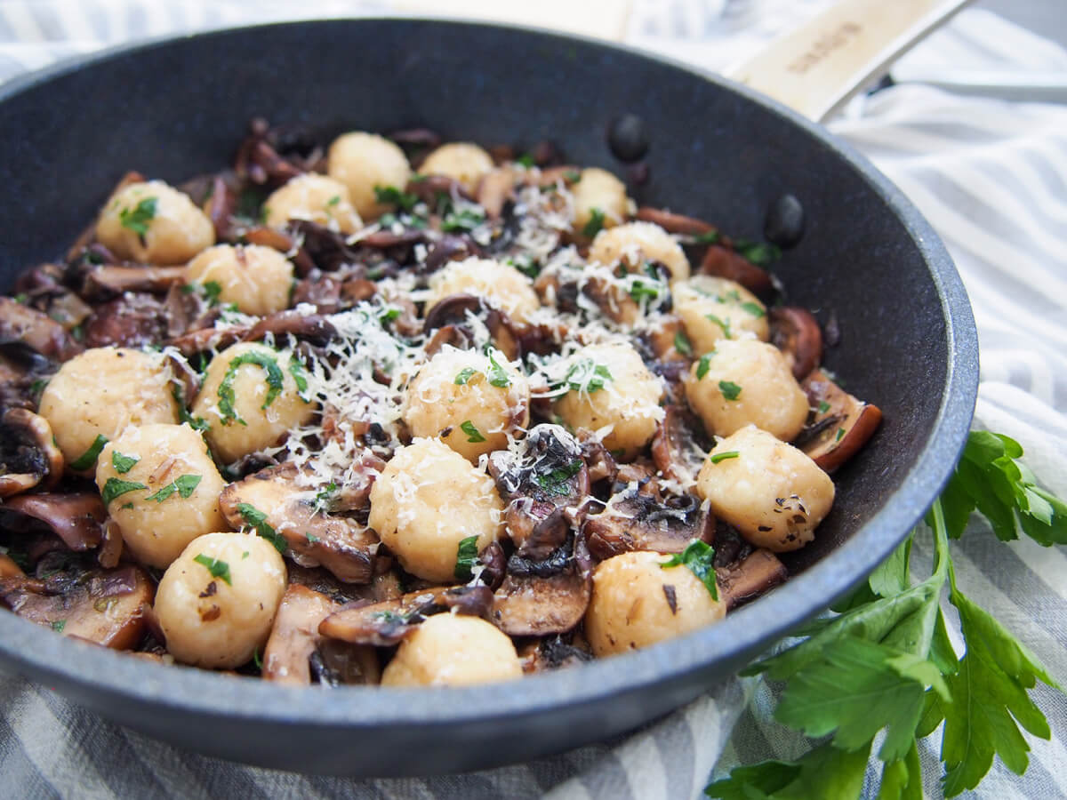 mushroom gnocchi in skillet with parsley sprig to side