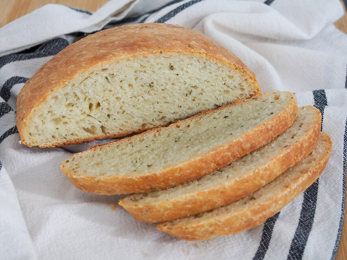 slices of no knead olive oil rosemary bread in front of rest of loaf