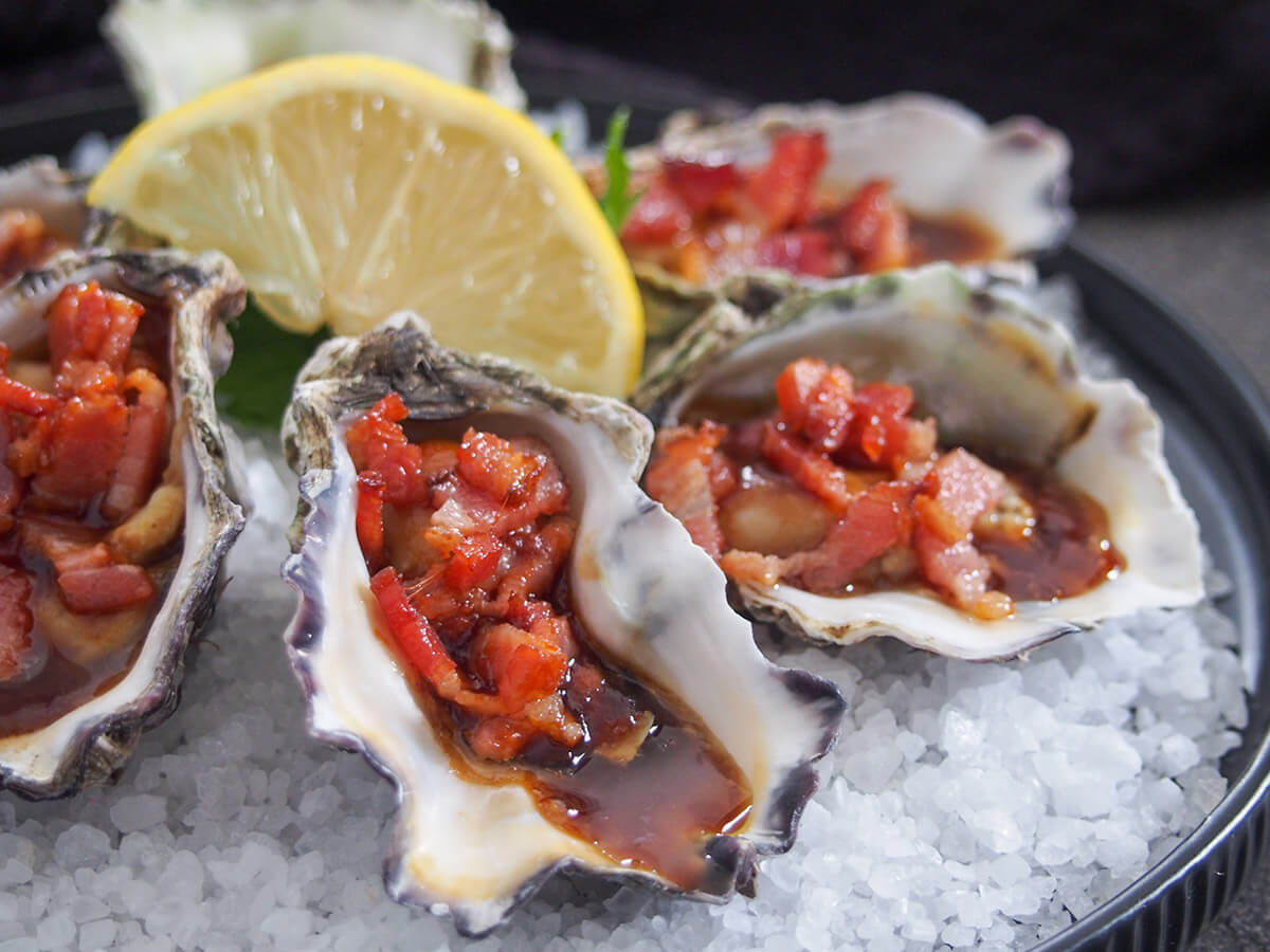 close up of oysters Kilpatrick from side