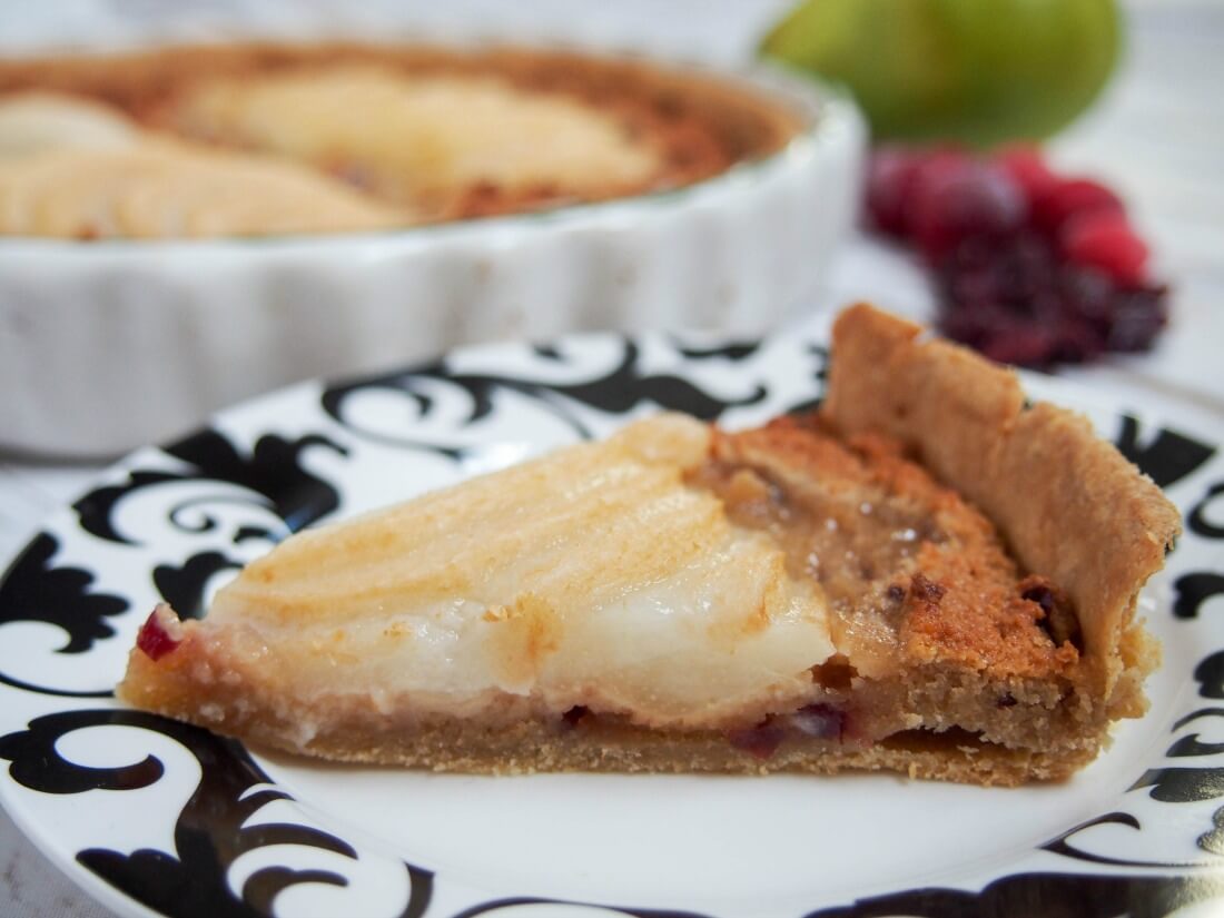 slice of pear frangipane tart with cranberries on plate