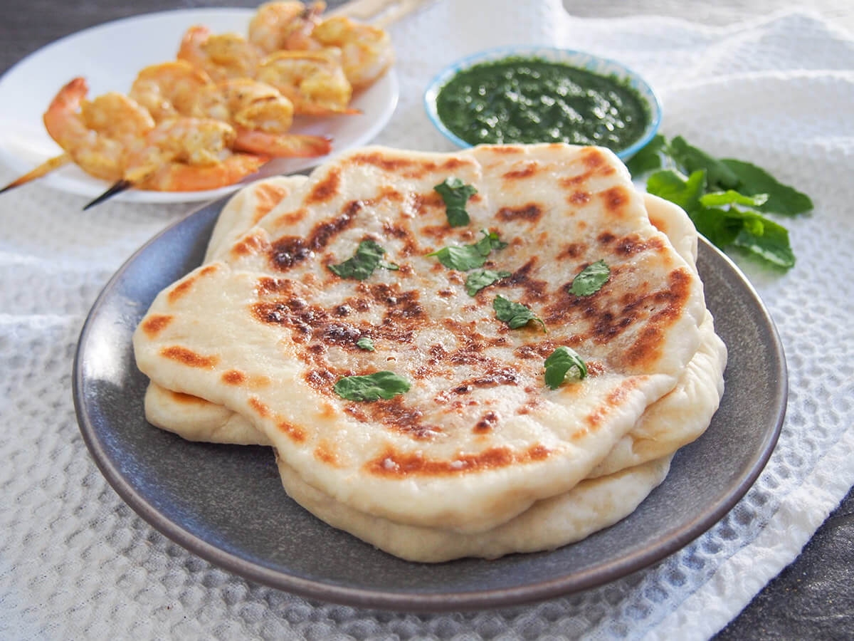 peshwari naan on plate with shrimp and chutney behind