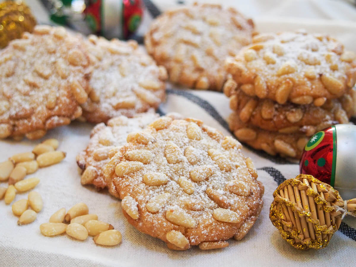 pignoli cookies dusted with powdered sugar with decorations to side