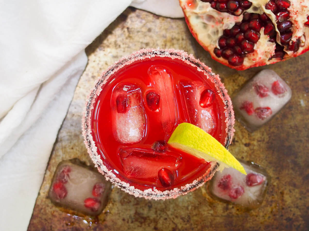 glass of pomegranate margarita from overhead with pomegranate to side