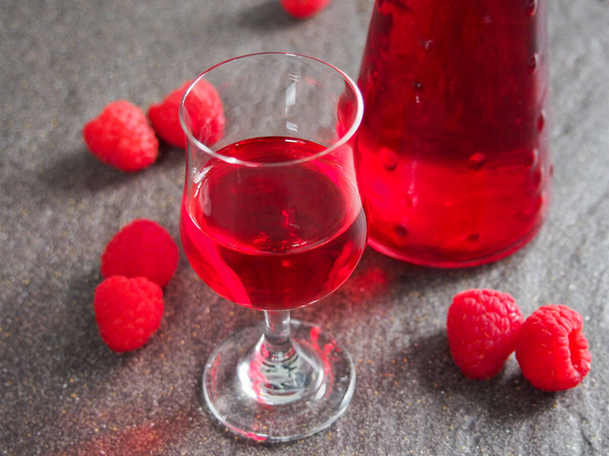 glass of raspberry liqueur with bottom of bottle behind