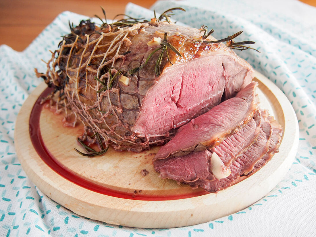 whole roast lamb on chopping board with slices to front