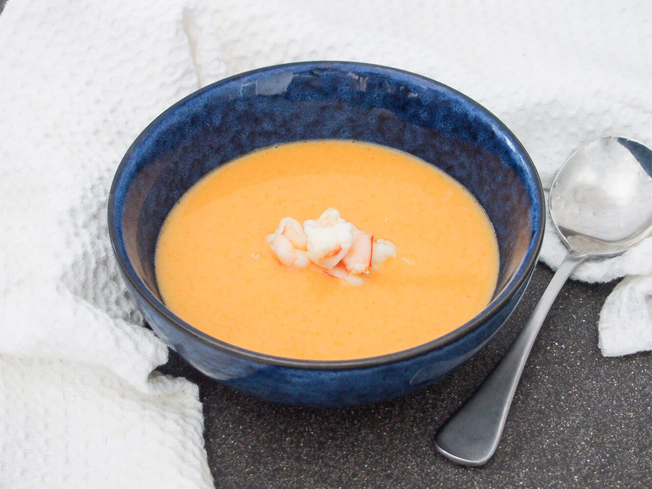 bowl of shrimp bisque with spoon to side