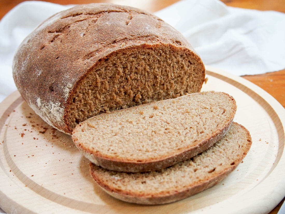 sourdough rye bread side on with slices in front of rest of loaf