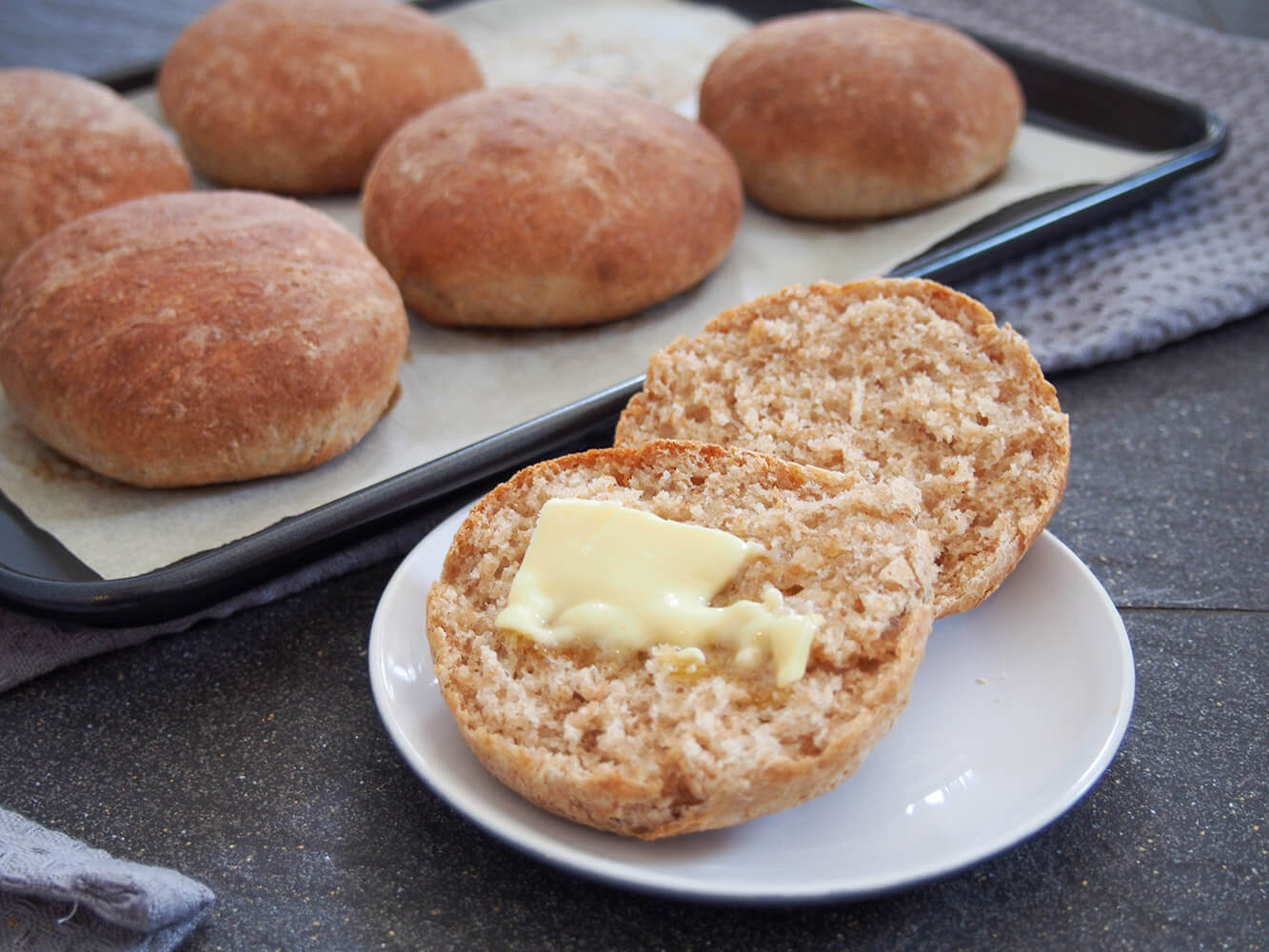 finished bread roll with butter on top and other rolls behind