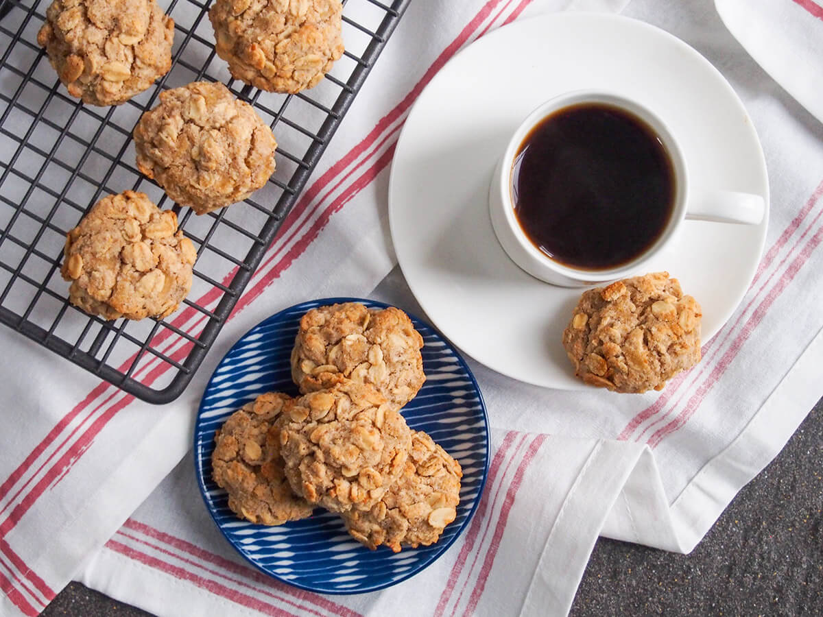 small plate of spiced maple oatmeal cookies with another on saucer by coffee cup and more cookies on cooling rack to left all from overhead