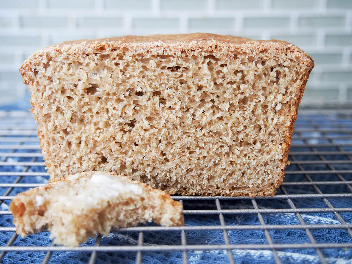 Sprouted wheat bread loaf with buttered piece in front