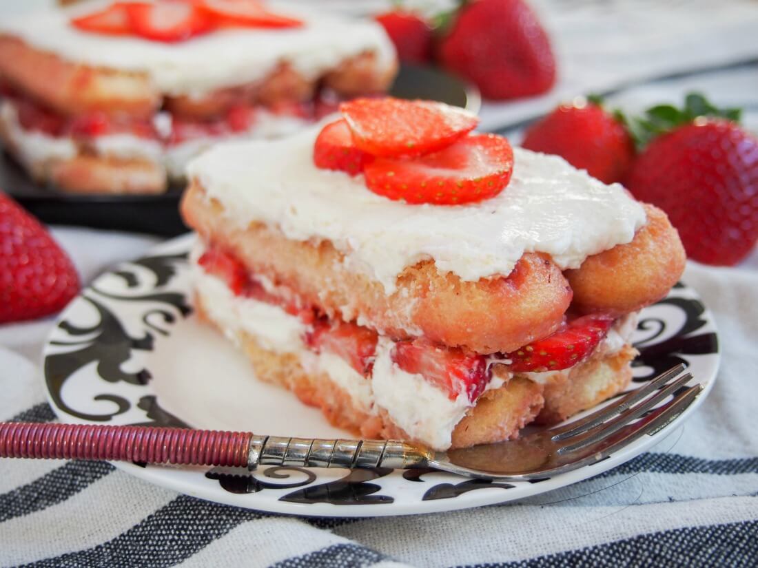 piece of strawberry tiramisu on a plate with a fork in front