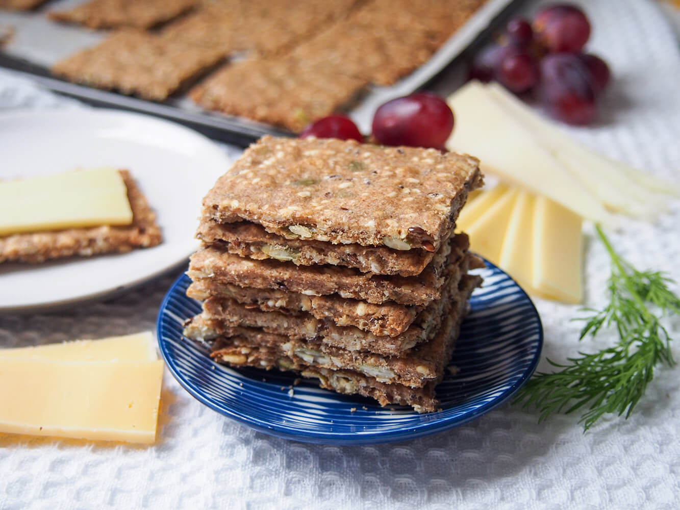 stack of Swedish crispbread (rye seed crackers) on small plate with cheese behind