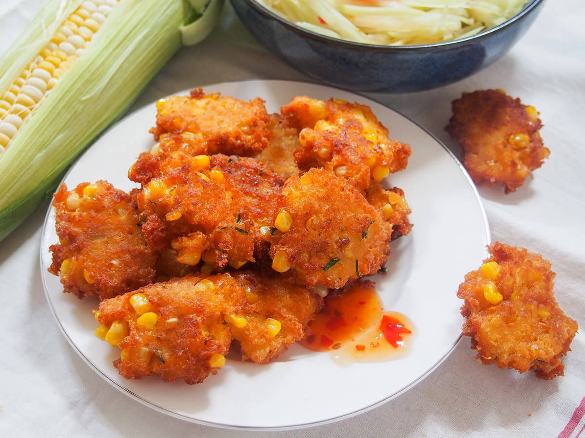 plate of Thai corn fritters with cob of corn to side