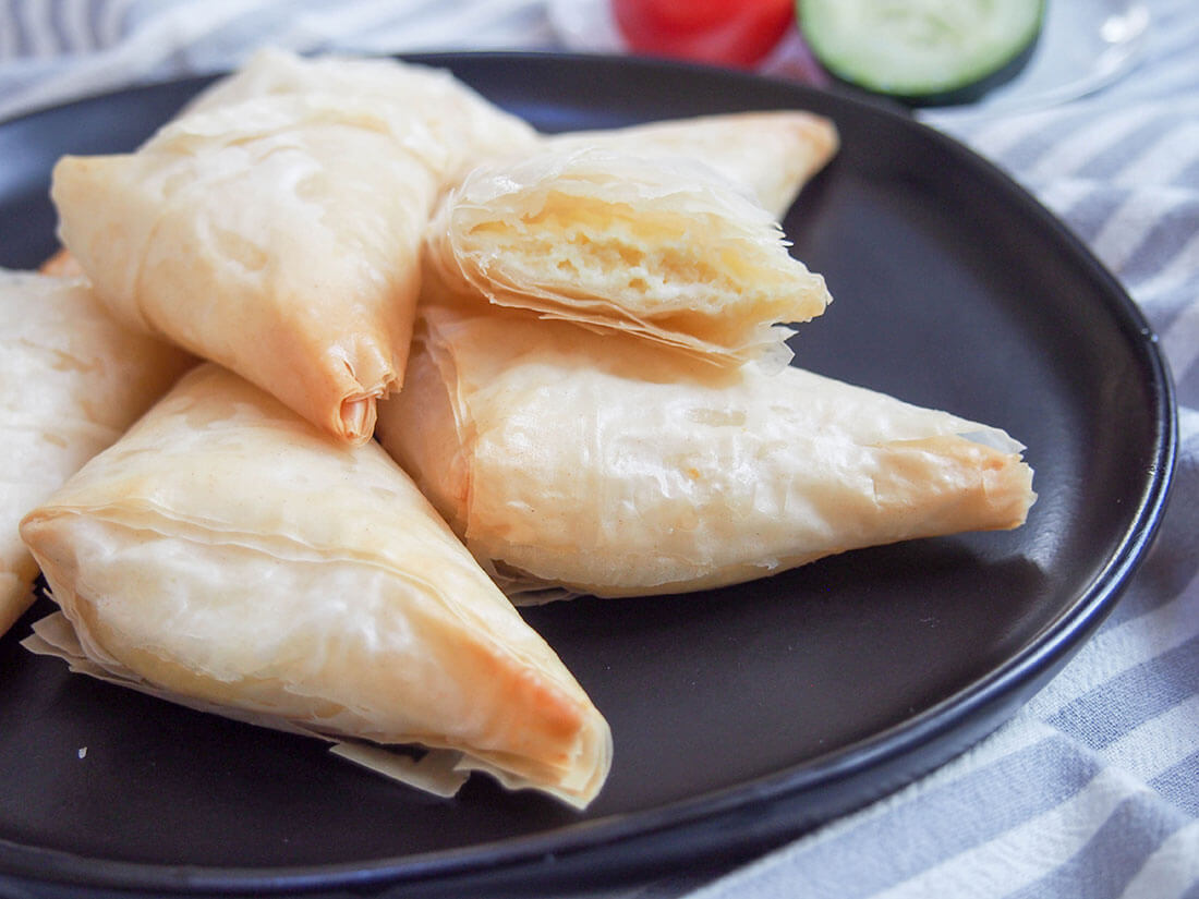 tiropita Greek cheese pastries on plate with one open showing filling