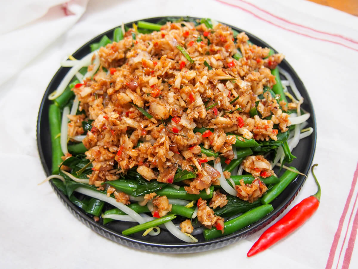 plate of Urap sayur (Indonesian vegetables with coconut topping) with red chili to side