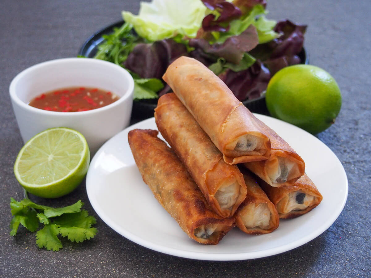 plate of Vietnamese fried spring rolls with nuam choc and limes to side