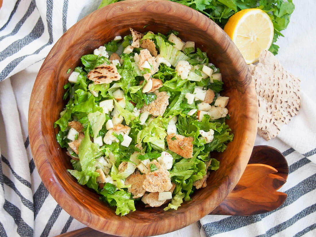 bowl of winter fattoush salad from overhead with lemon and pita to side