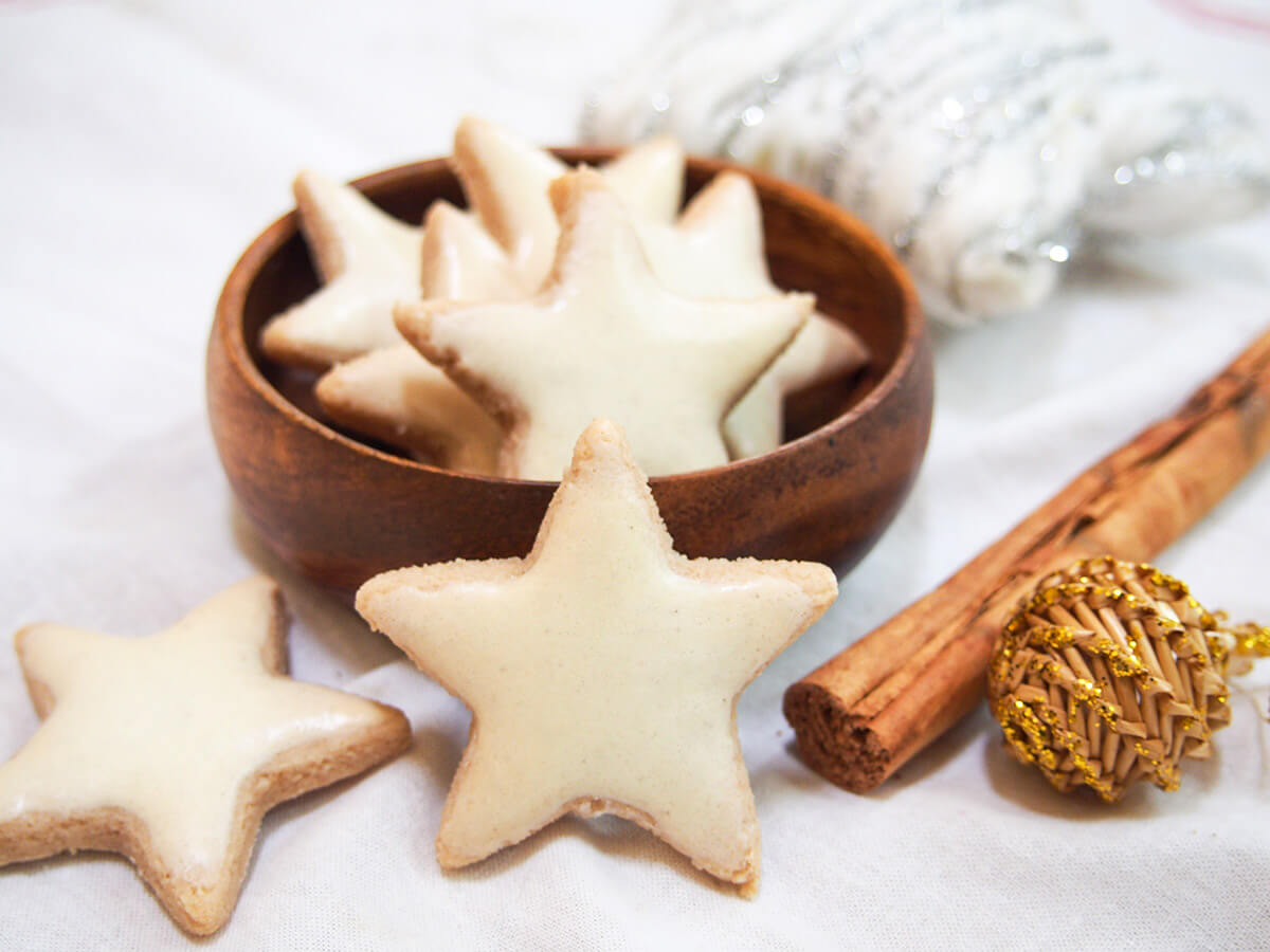 zimtsterne cinnamon star cookies in bowl with one standing in front and cinnamon stick to side